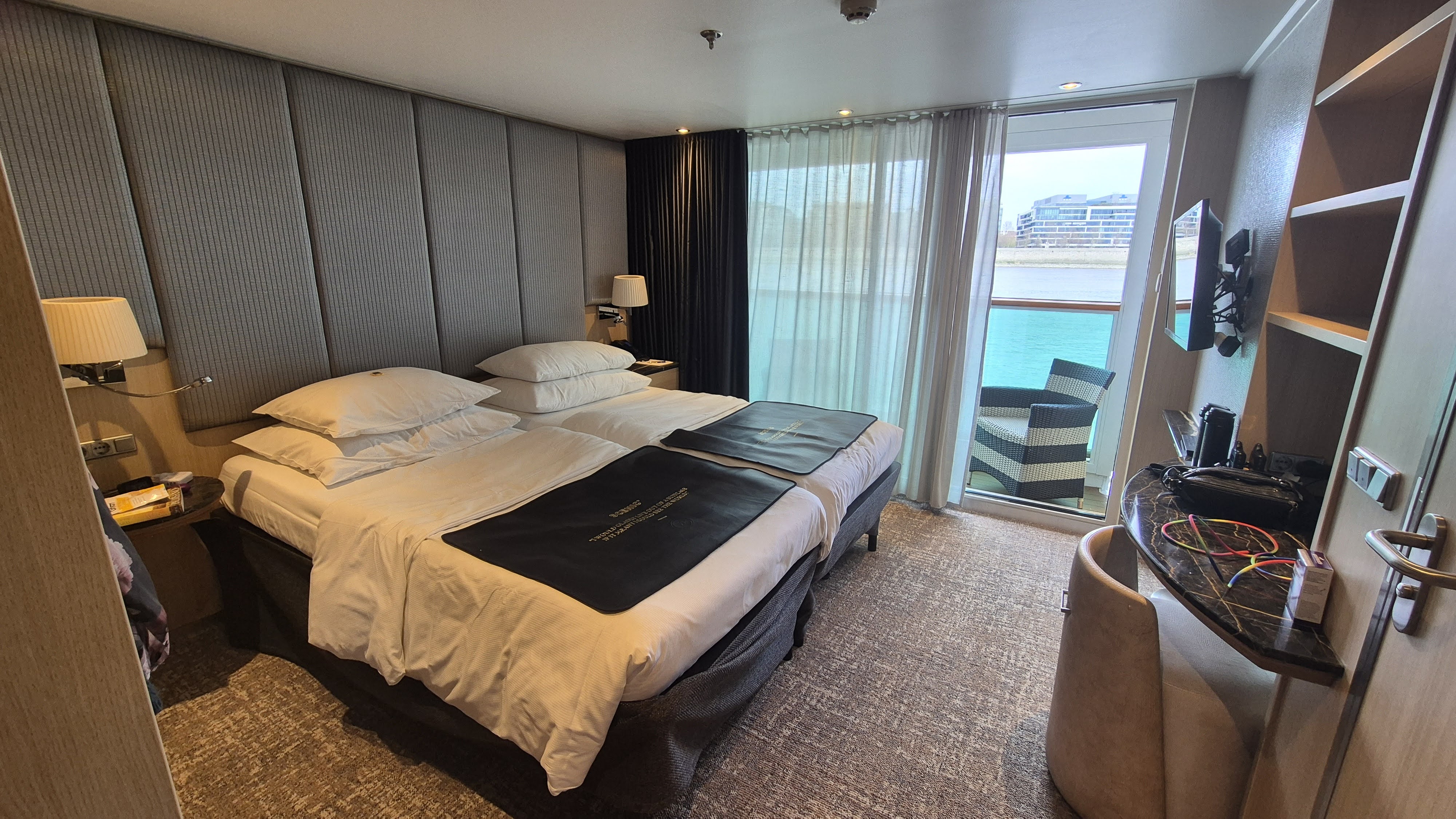 The bedroom of a Balcony Suite on Scenic Crystal, with the bed facing the window onto the river