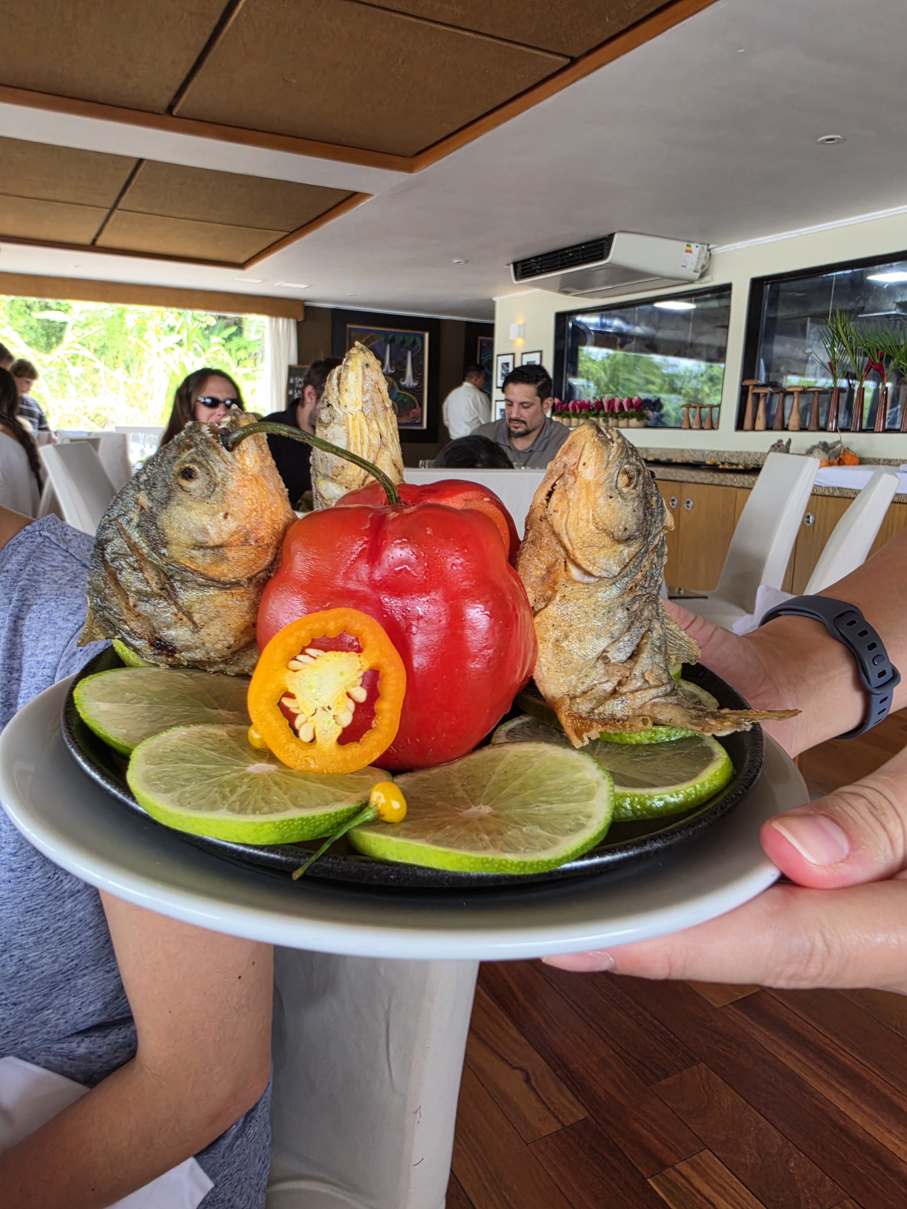 Fried piranha served on a platter with lime and peppers in the dining room