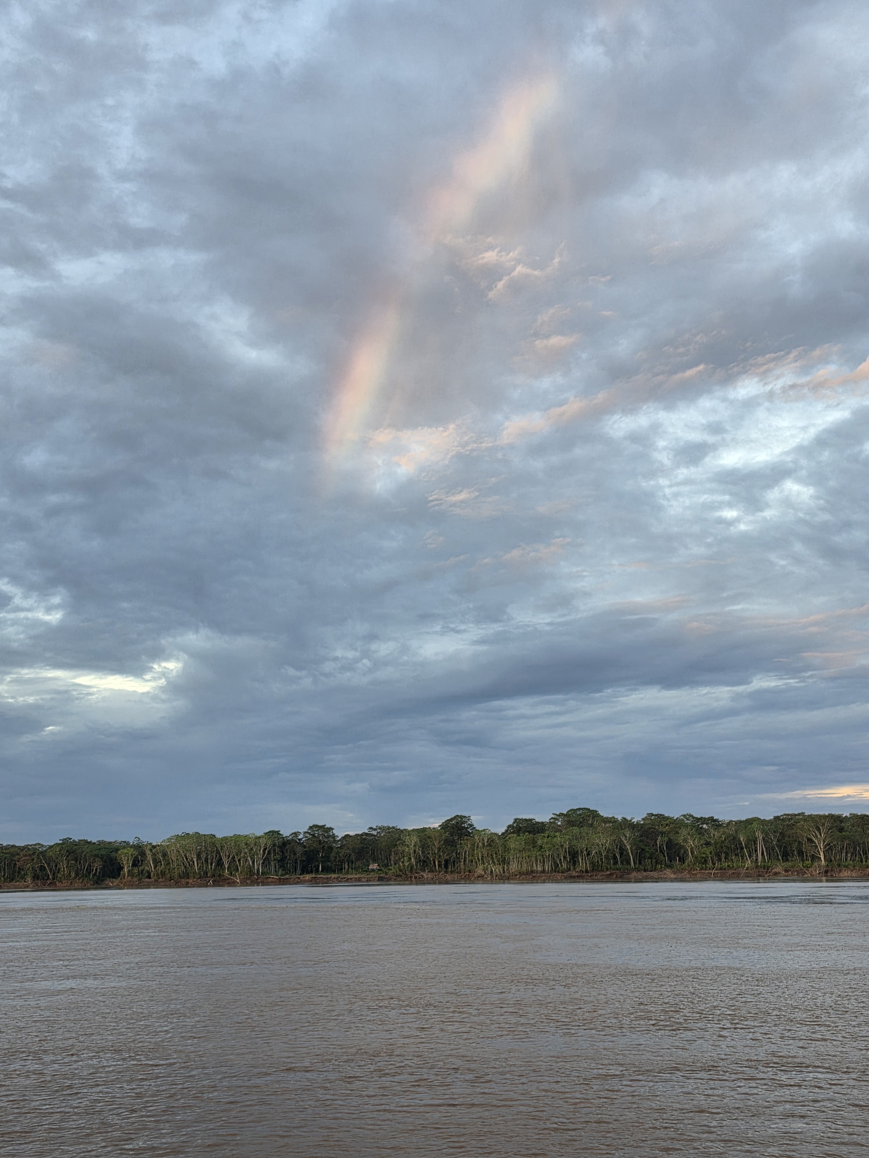 A rainbow in the clouds above the rainforest at the birthplace of the Amazon