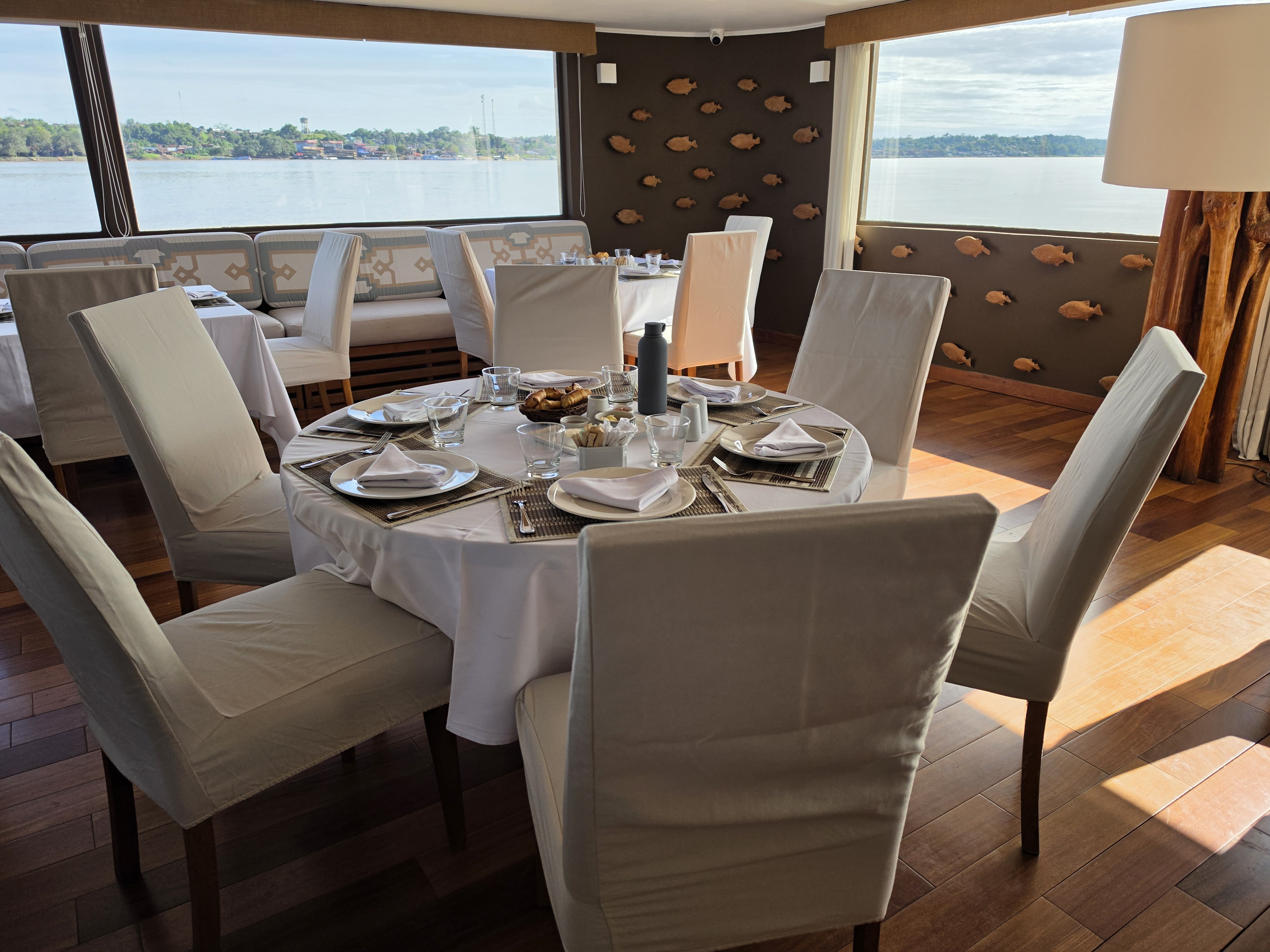 The dining room on Delfin III, set with a round table and windows onto the river
