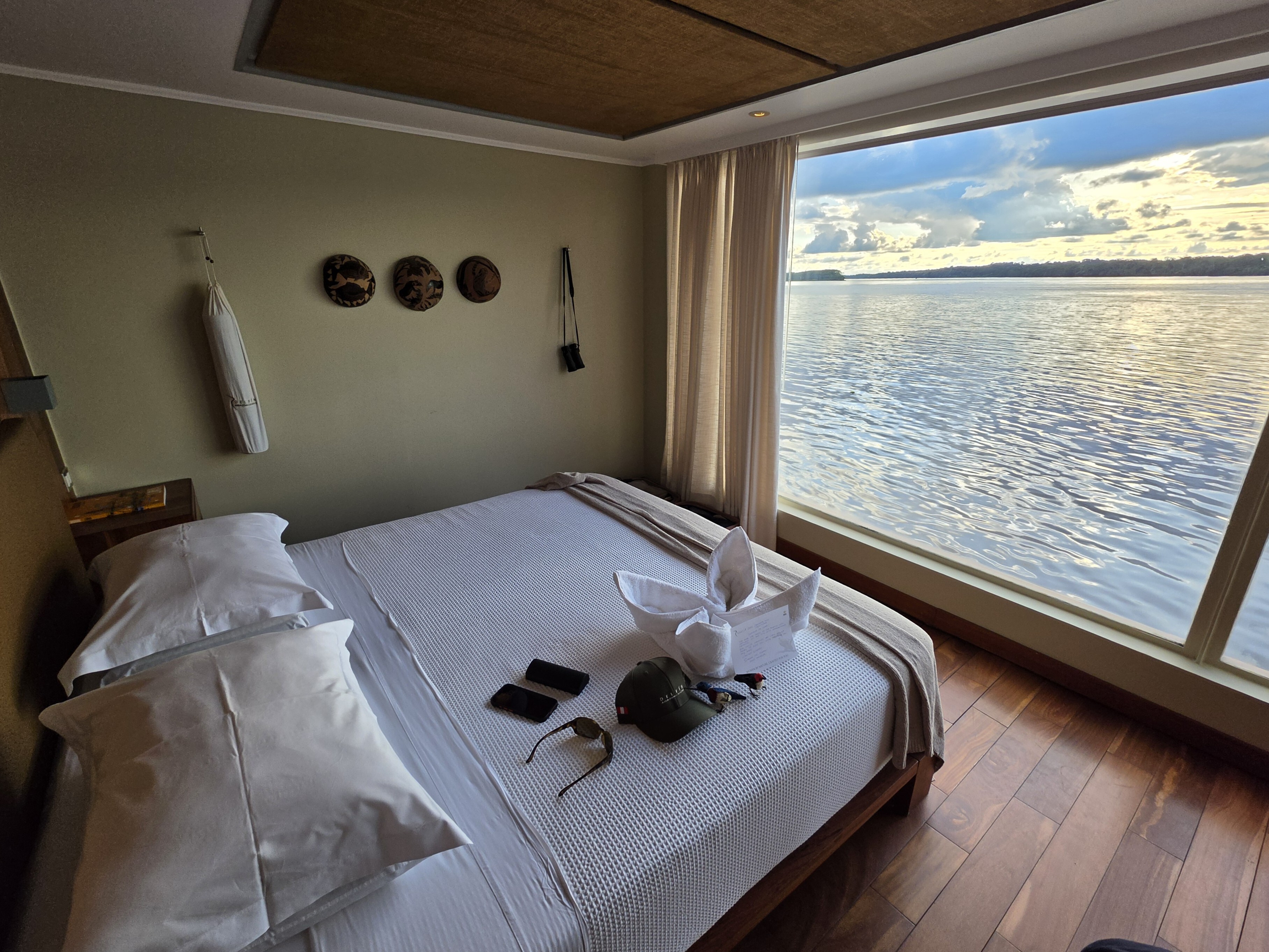 A suite on Delfin III with a bed facing a floor-to-ceiling window over the river