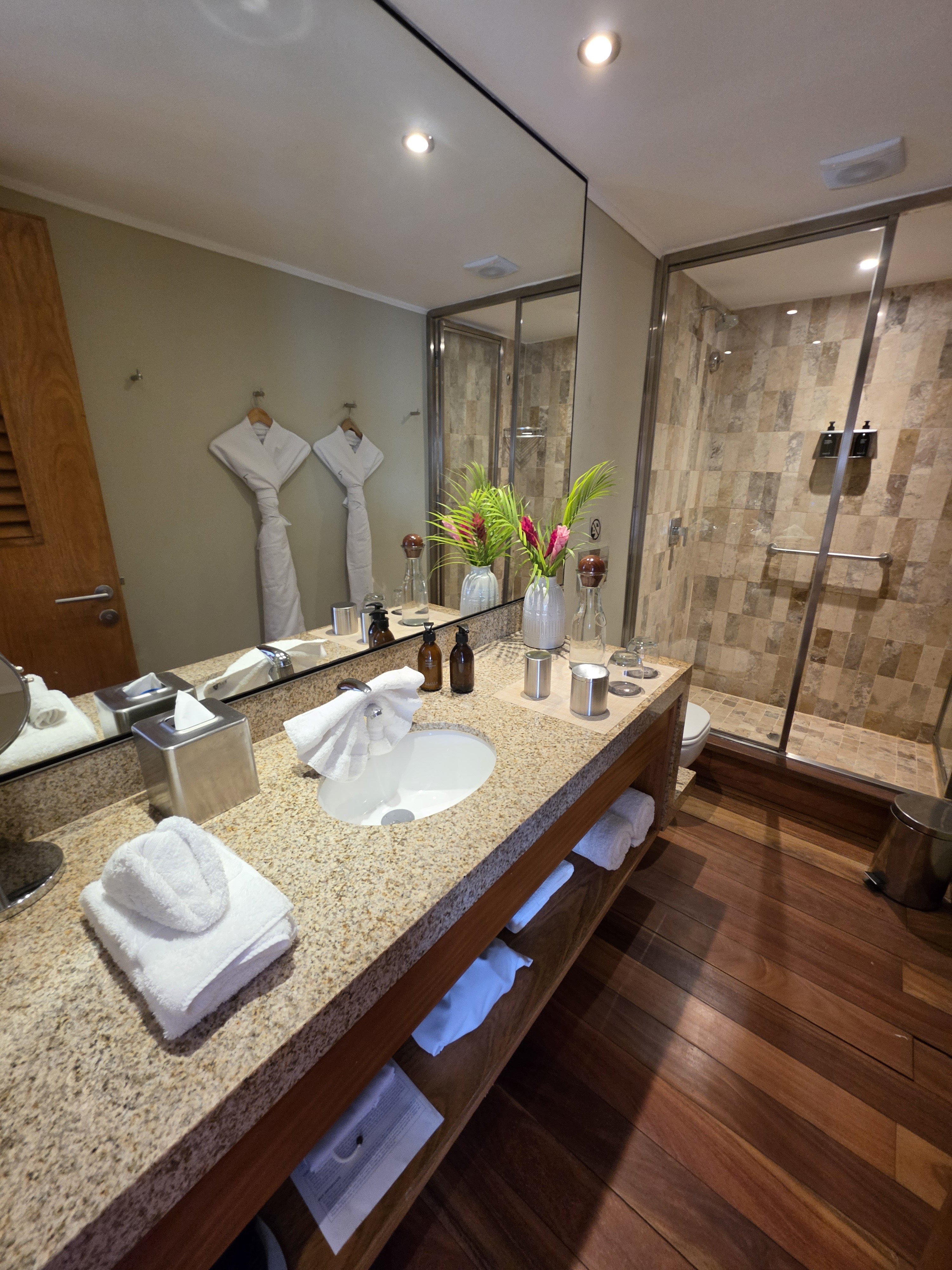The suite bathroom on Delfin III with twin robes and a walk-in shower